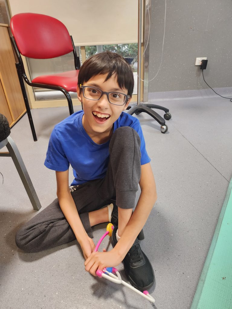 A smiling boy crouched on the ground.